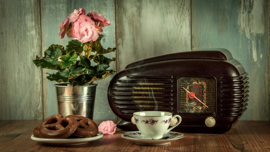 old fashioned radio on a kitchen table with donuts and coffee
