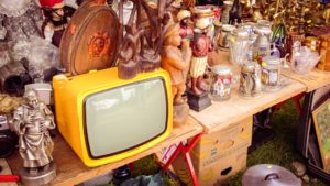 tv set in an antique shop surrounded by other antiques
